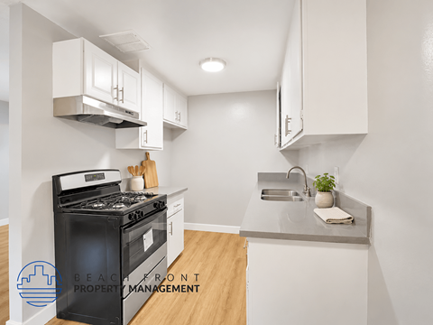 A modern kitchen with a black stove top oven and white cabinets.