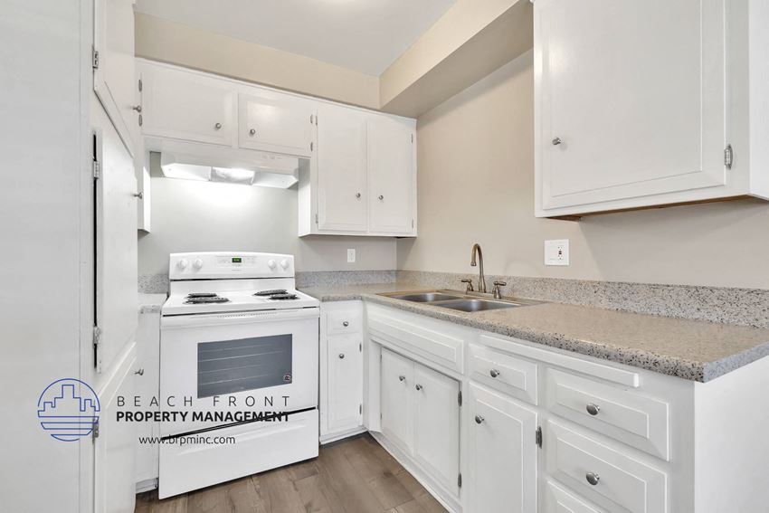 a white kitchen with granite counter tops and white appliances