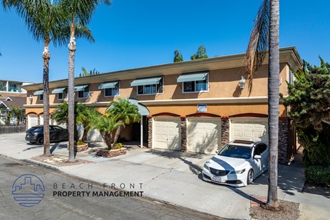 A white car is parked in front of a building with the sign "BEACH FRONT PROPERTY MANAGEMENT".