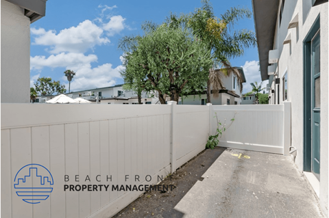 a white privacy fence in front of a house with a sidewalk