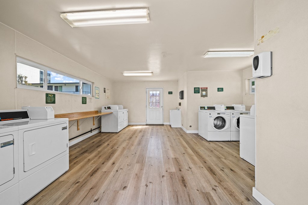 a washer and dryer room with wood floors and white appliances