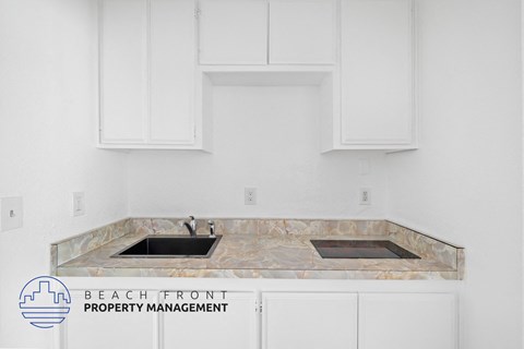 A kitchen with a marble countertop and white cabinets.