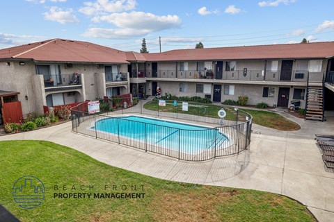 A swimming pool is surrounded by a fence in a courtyard.