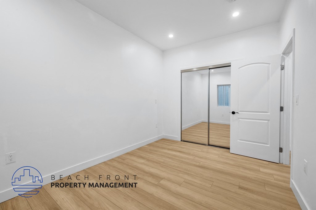 a bedroom with white walls and wood flooring and a white door