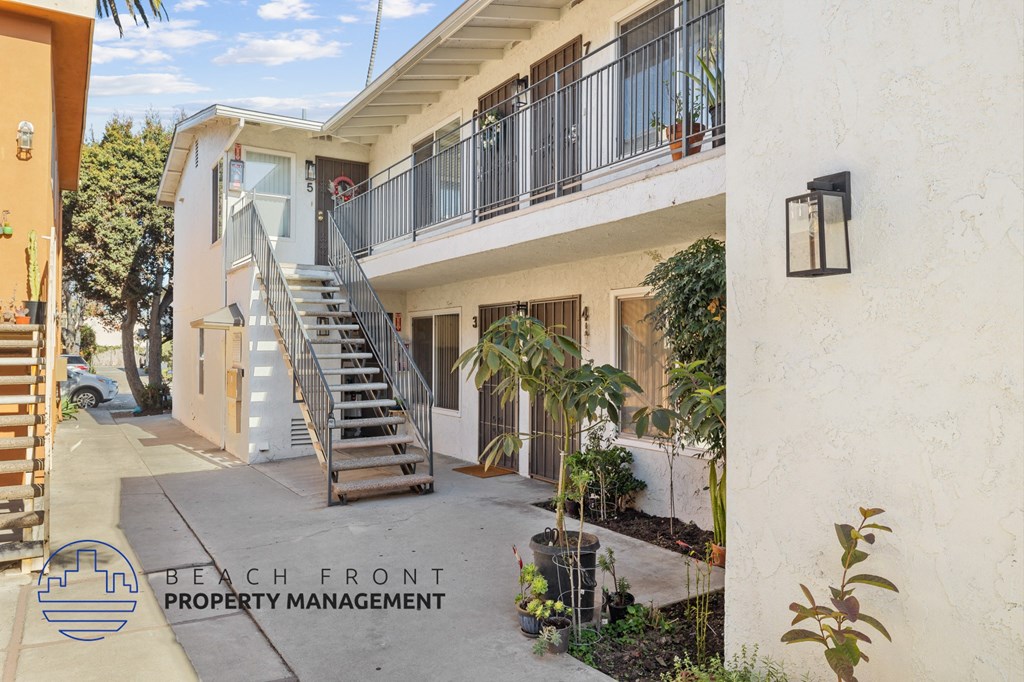 A white building with a balcony and a staircase leading to the balcony.