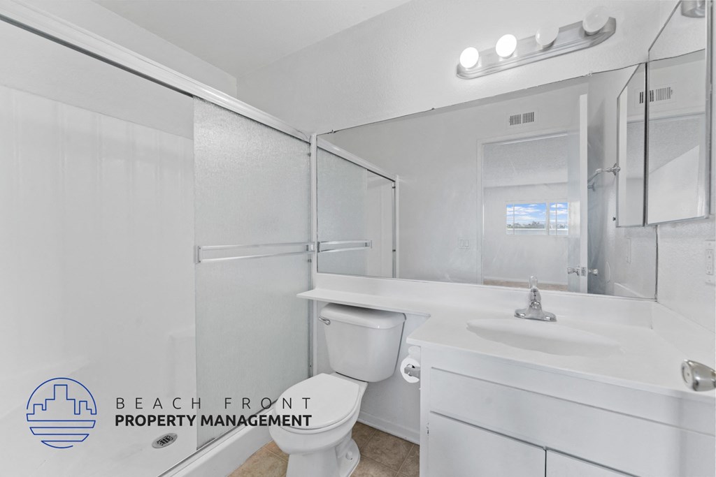 A white bathroom with a toilet, sink, and mirror.