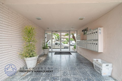A hallway with a plant and a sign for Beach Front Property Management.
