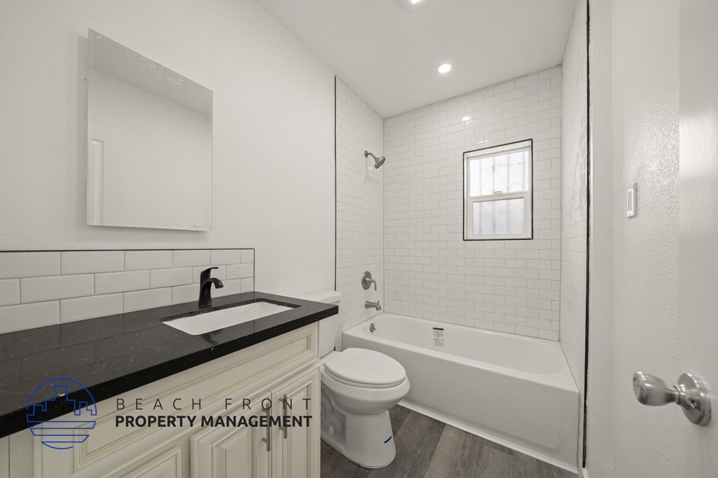 A bathroom with a black countertop and white fixtures.