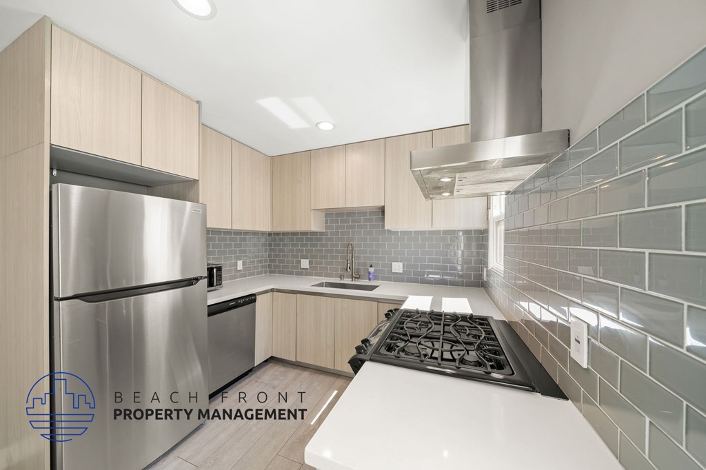 A modern kitchen with a stainless steel refrigerator and a stove top oven.