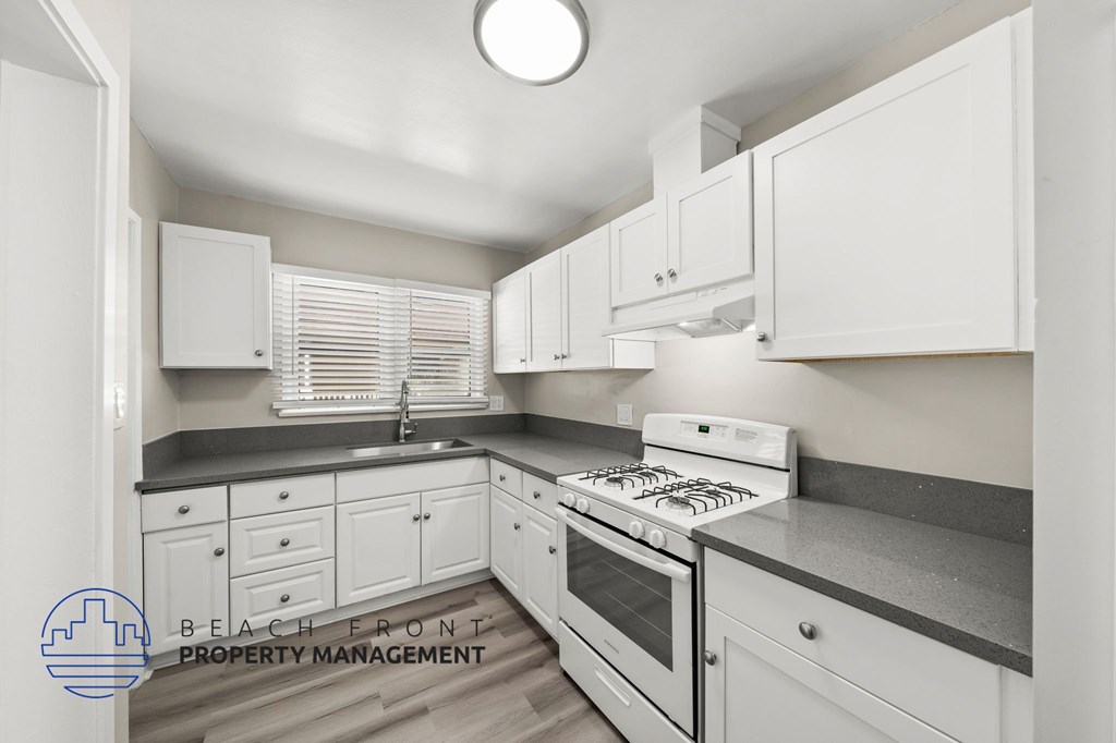 A kitchen with white cabinets and a stove top oven.