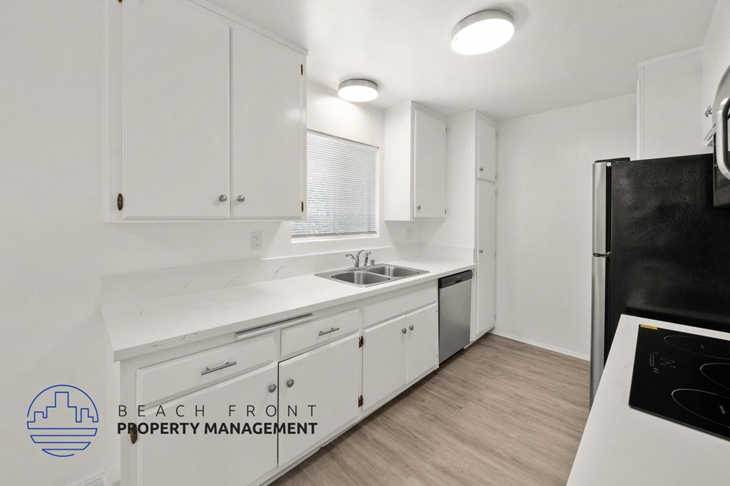 A kitchen with white cabinets and a black refrigerator.