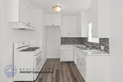 A kitchen with white cabinets and a wooden floor.