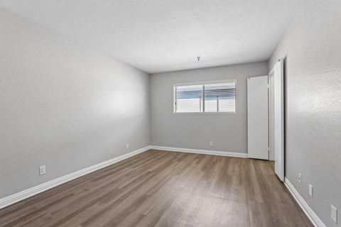 A room with wooden flooring and a window with blinds.