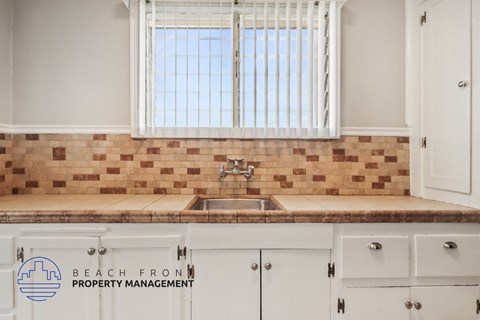A kitchen with a sink and a window with blinds.