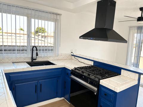 A kitchen with blue cabinets and a black range hood.