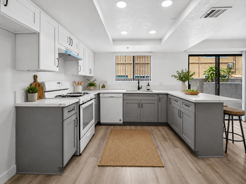 A modern kitchen with white cabinets and a wooden floor.