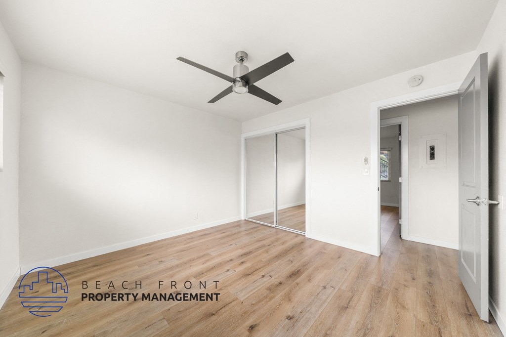 A room with a ceiling fan and a logo for Beach Front Property Management.