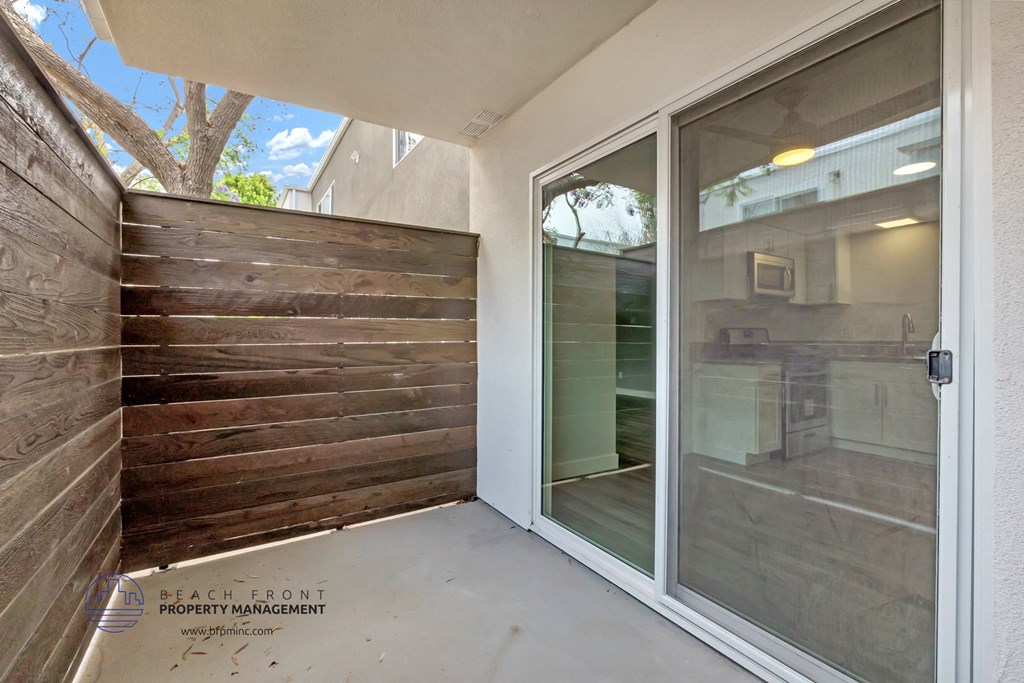 a patio with a wood privacy fence and a glass door