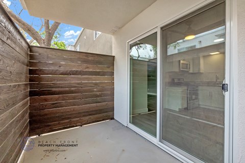 a patio with a wood privacy fence and a glass door