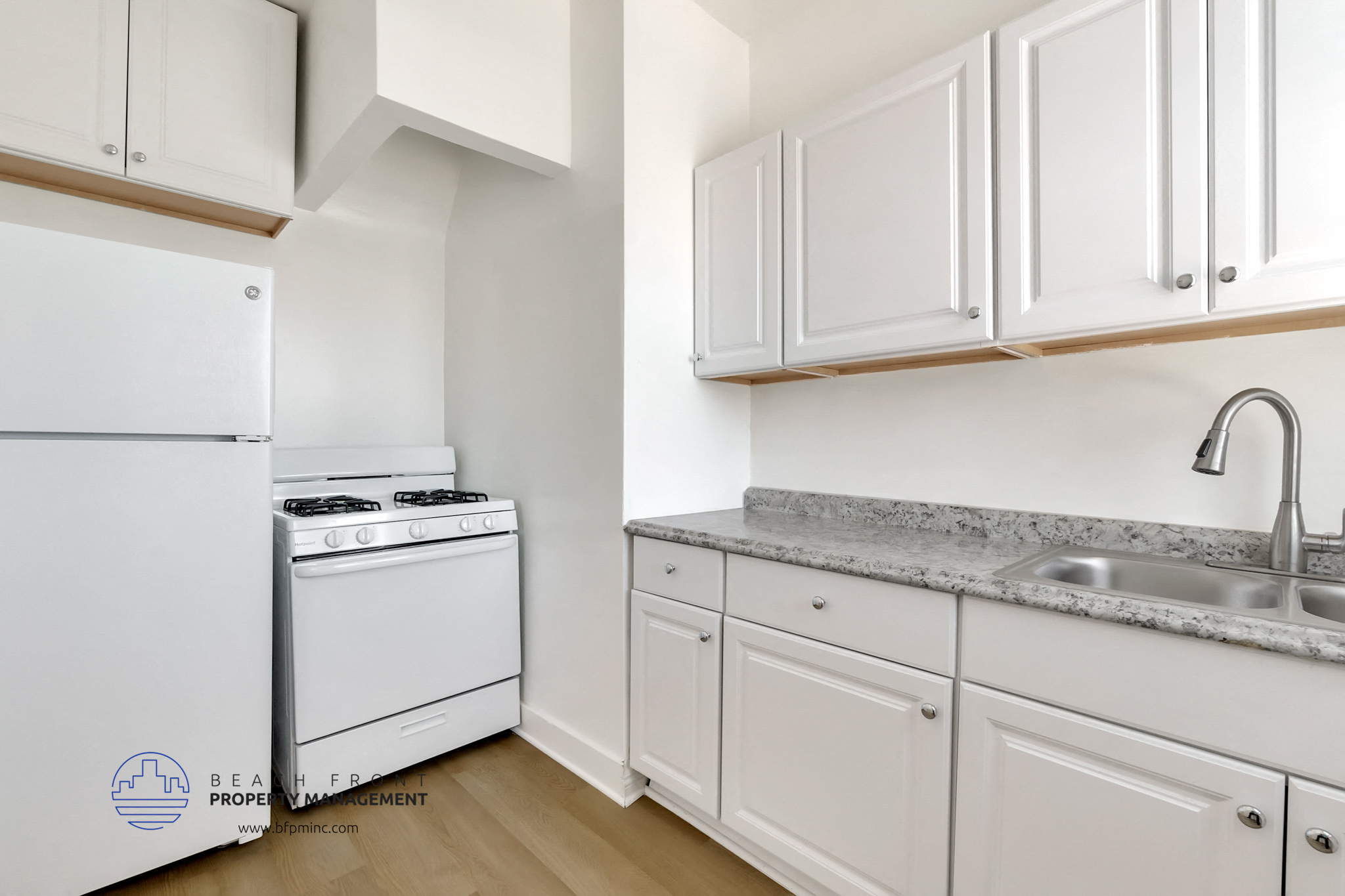 a kitchen with white cabinets and white appliances and a sink