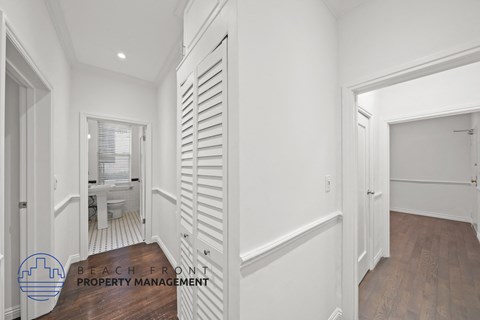 a white hallway with white shutters and a door to a bathroom