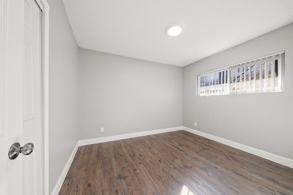 an empty living room with wood flooring and a window