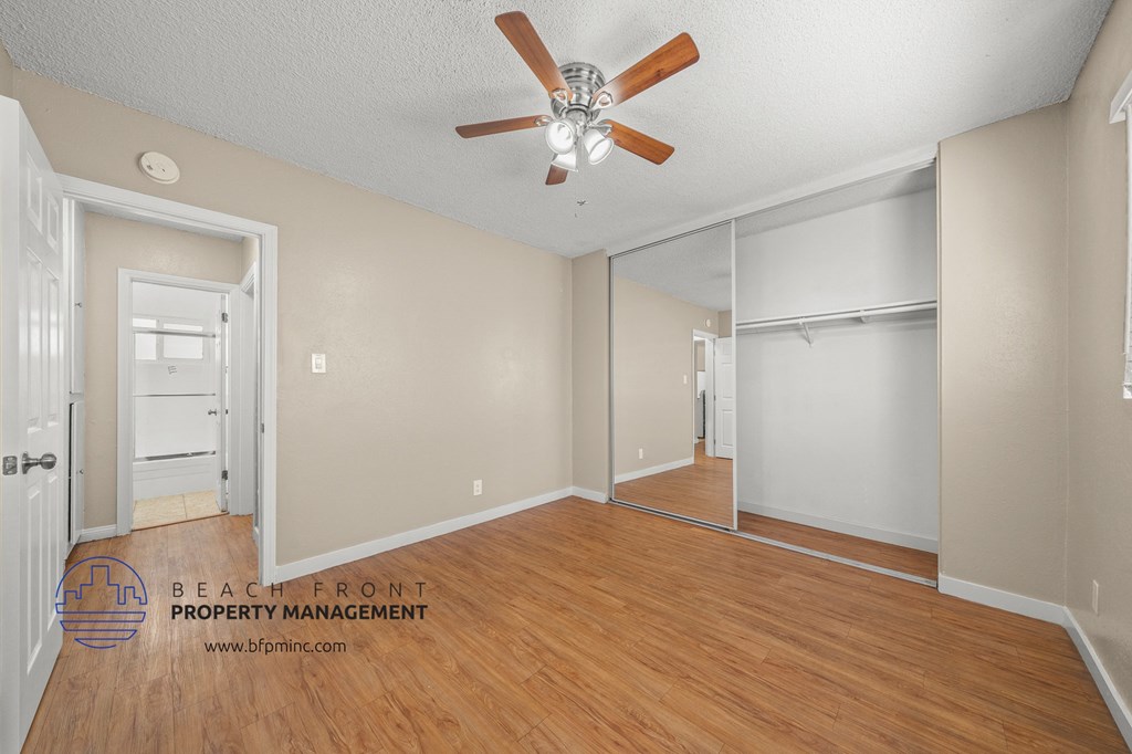 the living room and dining room with wood flooring and a ceiling fan