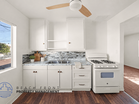 A kitchen with white cabinets and a wooden floor.