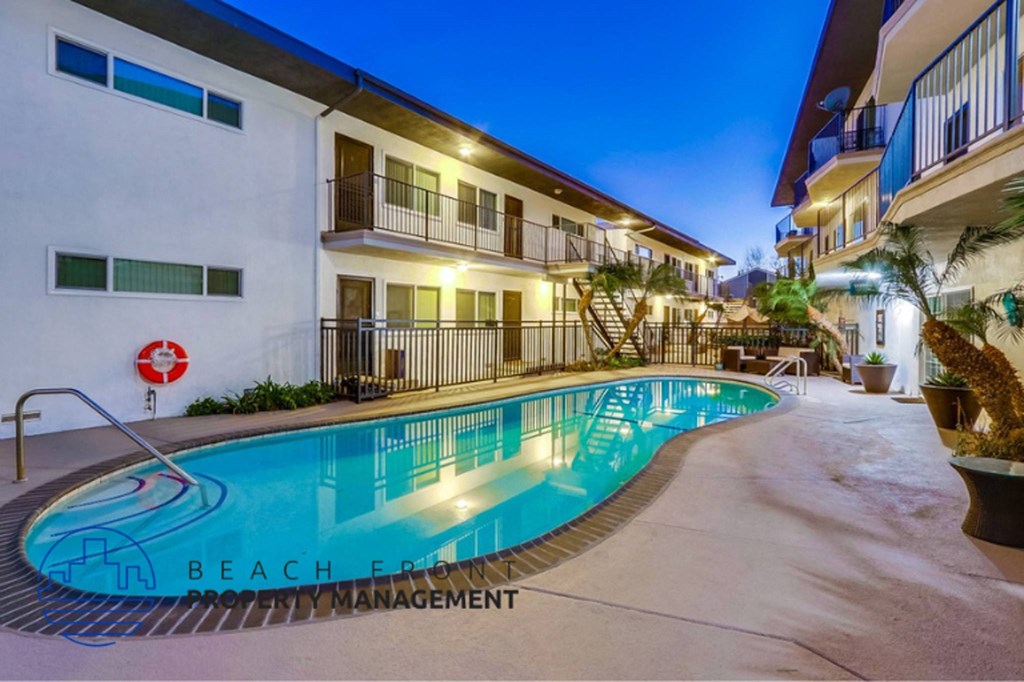 a resort style swimming pool at night in front of a building