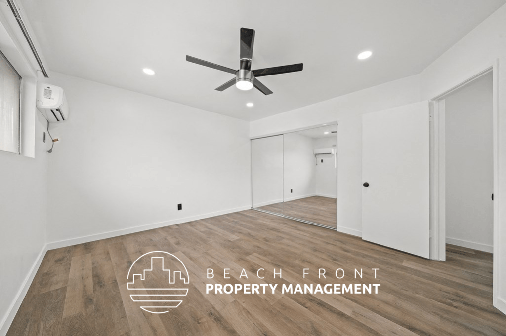 a living room with white walls and a ceiling fan