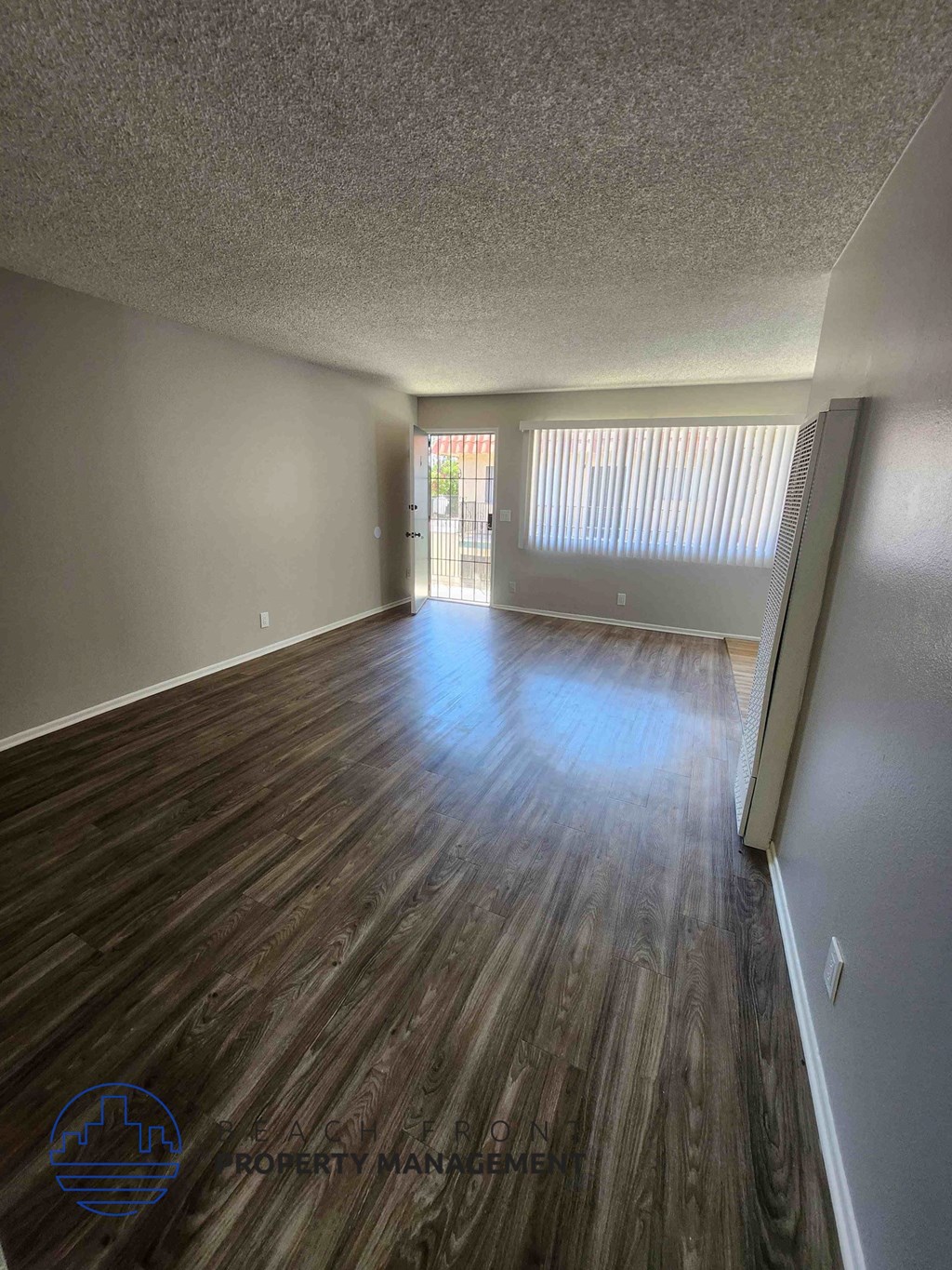 A room with wooden flooring and a window with blinds.