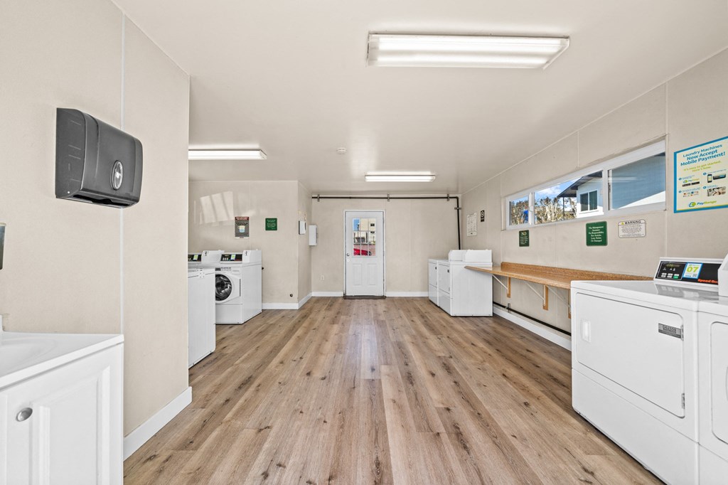 a laundry room with washes and dryers and a wood floor