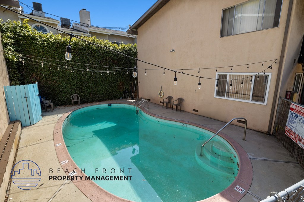 a backyard swimming pool with a building and a chain link fence