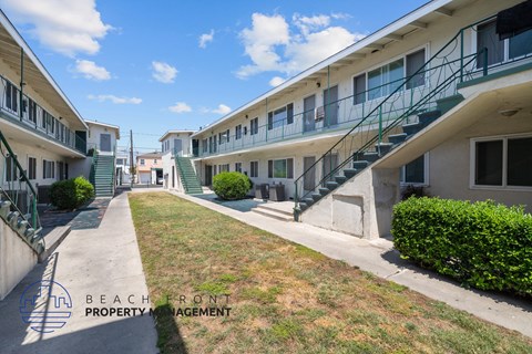 an exterior view of an apartment building with stairs and a lawn