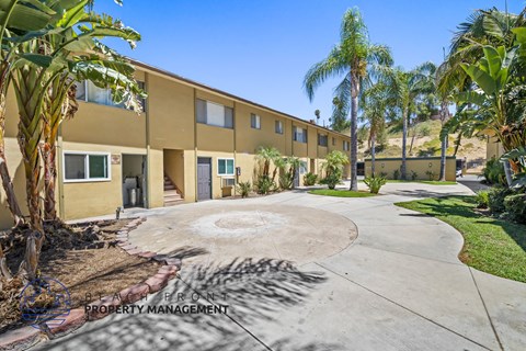 a yellow building with palm trees and a circular driveway