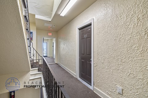 the upstairs hallway of a building with a brown door and stairs