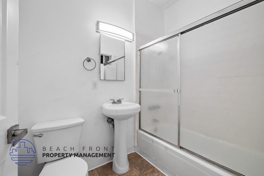 A white bathroom with a toilet, sink, and mirror.