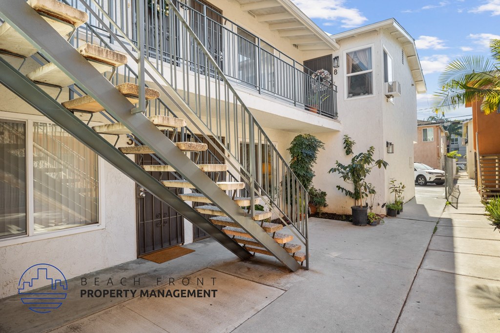 A staircase with a metal railing leads to a balcony with a white wall and a window.