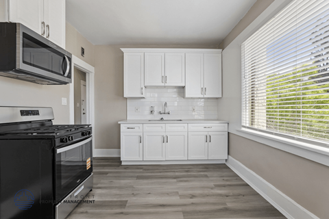 A kitchen with white cabinets and a black stove top oven.