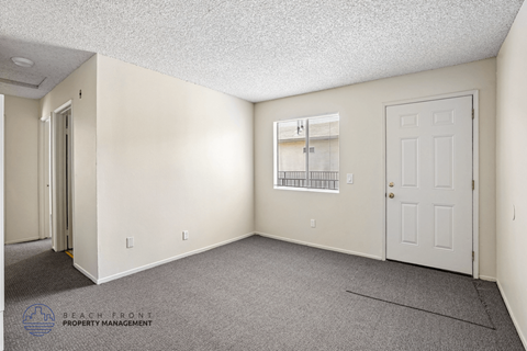 A sparsely furnished room with a window and a door.