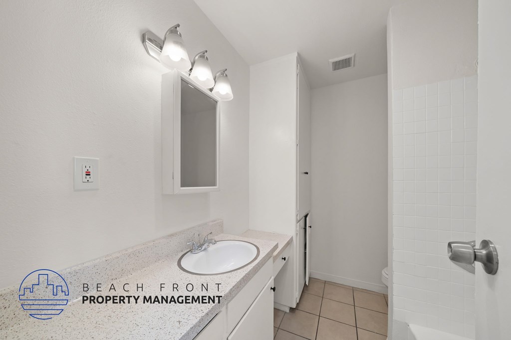 A bathroom with a sink, mirror, and shower.