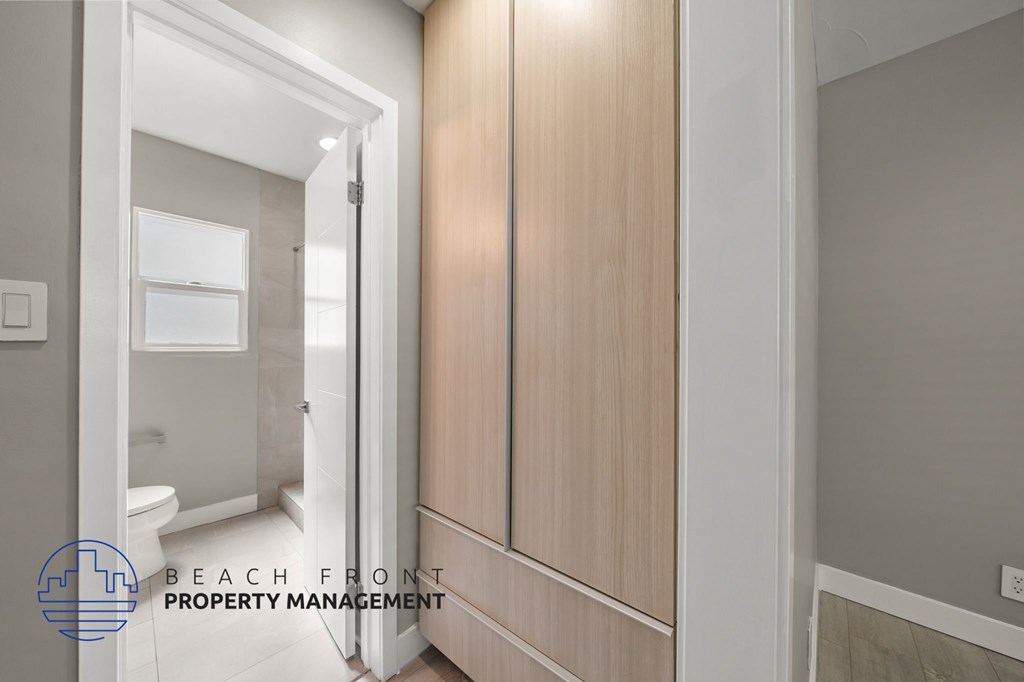 A bathroom with a toilet, sink, and wooden cabinetry.