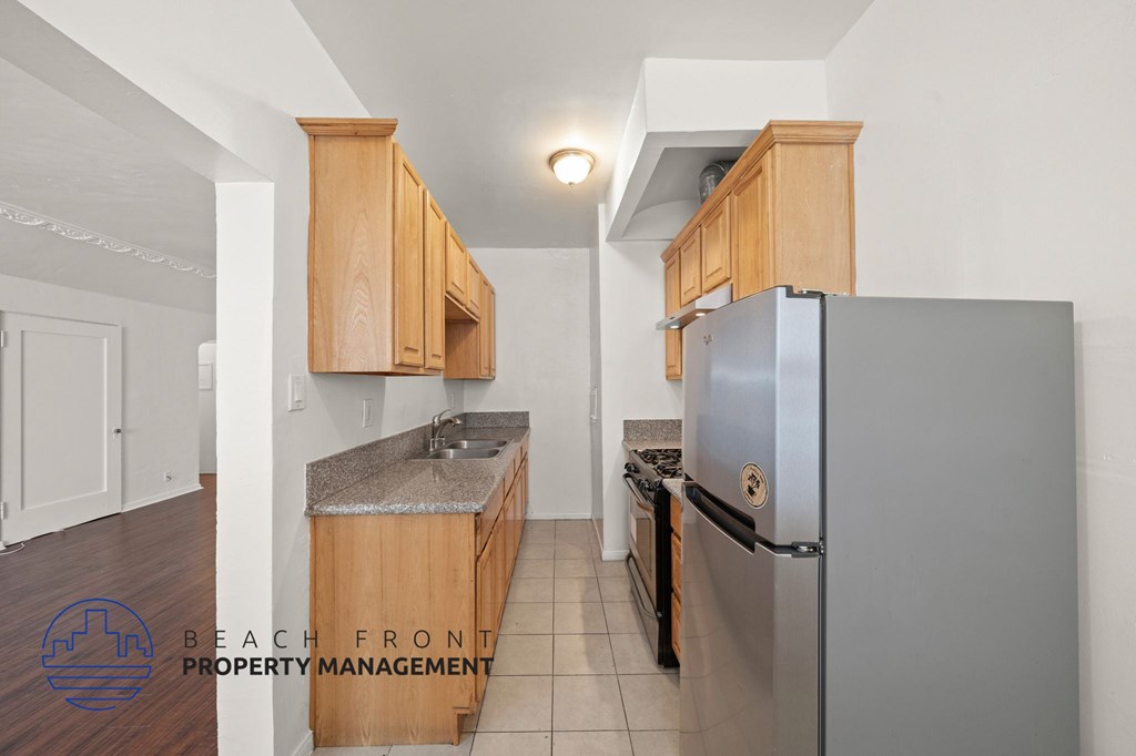 A kitchen with wooden cabinets and a stainless steel refrigerator.