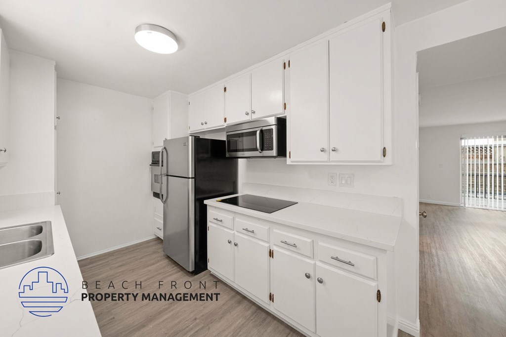 A kitchen with white cabinets and a stainless steel refrigerator.