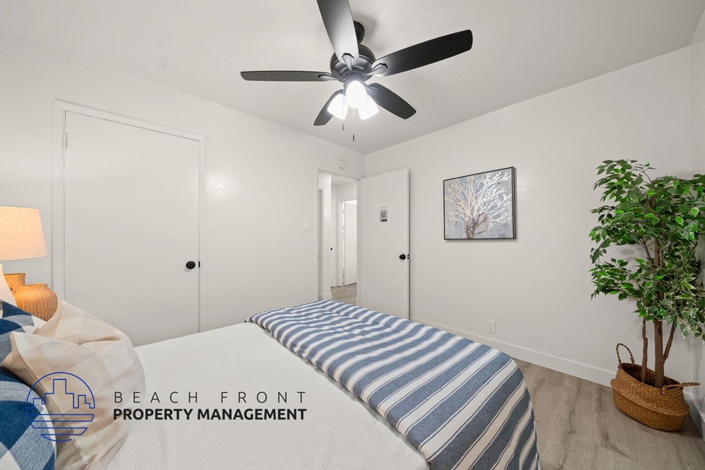 A room with a ceiling fan and a bed with a striped cover.