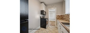 A kitchen with a black fridge and white cabinets.