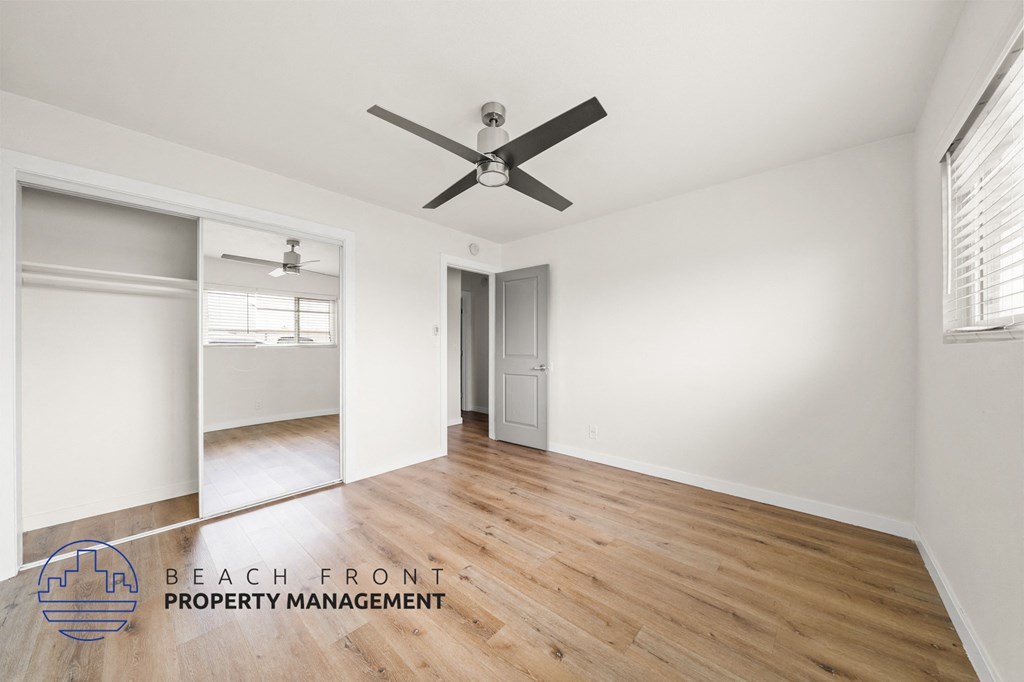 A spacious room with a ceiling fan and wooden flooring.