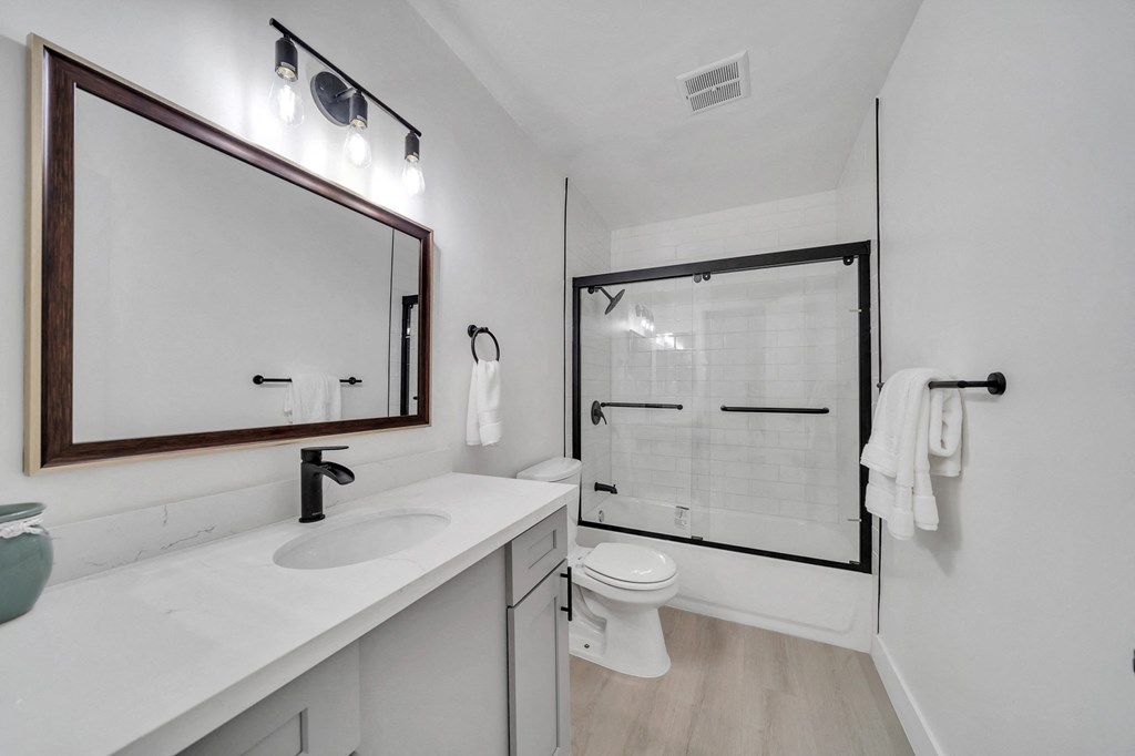 a white bathroom with a large mirror and a white toilet