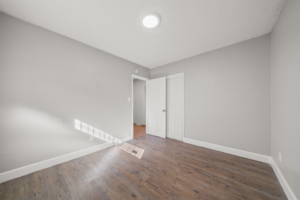 an empty living room with a hardwood floor and white walls