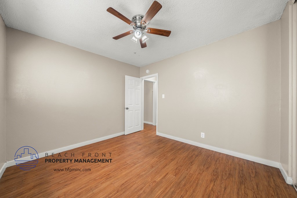 the living room of an apartment with wood flooring and a ceiling fan